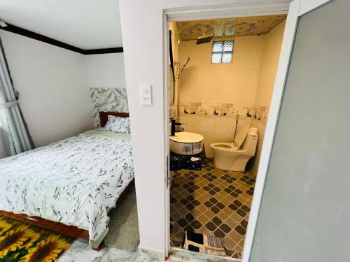 a bedroom with a bed and a bathroom with a toilet at Gió Homestay - Pleiku in Pleiku