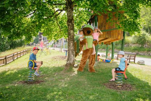 a group of children sitting on chairs under a tree at MONDI Resort und Chalet Oberstaufen in Oberstaufen