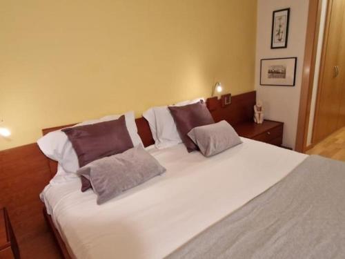 a large white bed with three pillows on it at Homing Sabadell 73 in Sabadell