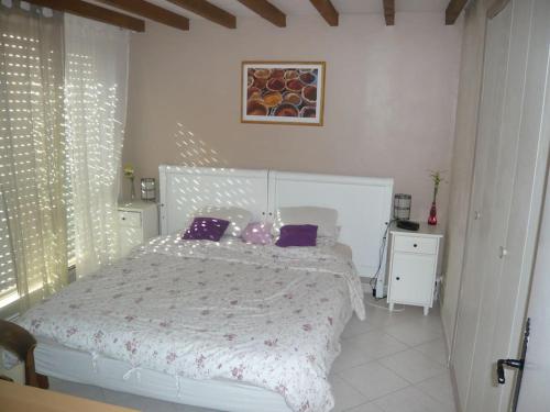um quarto com uma cama branca e almofadas roxas em Petite villa dans copropriété avec piscine et vue mer. em Hyères