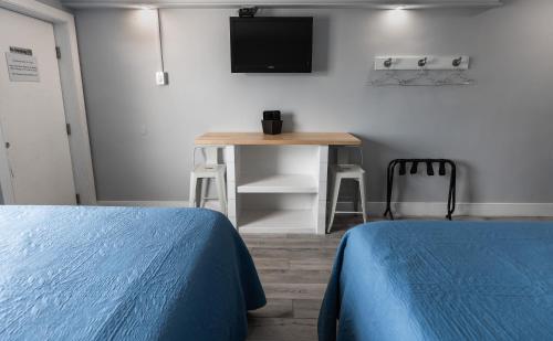 a room with two beds and a table with a television at Sea Horse Motel in Brant Beach