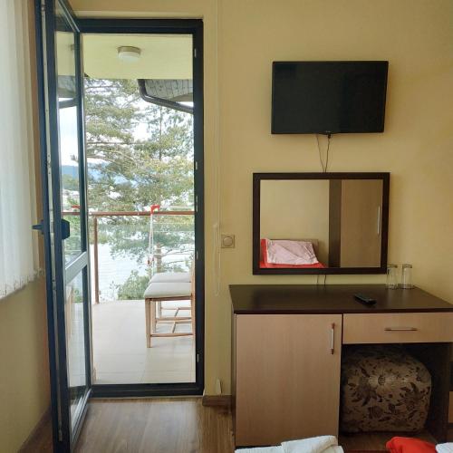 a room with a mirror and a television on the wall at Къща за гости СИАНА in Dospat