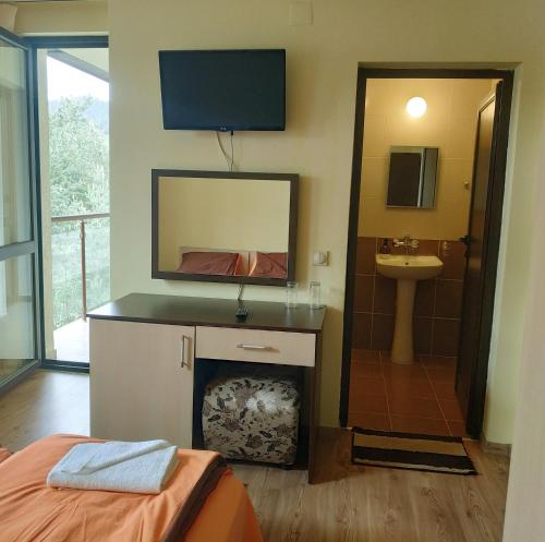 a room with a fireplace and a sink and a mirror at Къща за гости СИАНА in Dospat