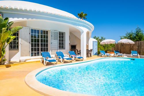 una piscina con sillas y una casa en Villa Menorca by Algarve Vacation, en Armação de Pêra