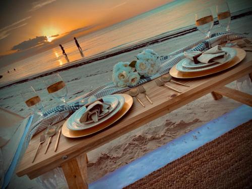 uma mesa de madeira com pratos e copos na praia em Picnic on the beach em Holbox