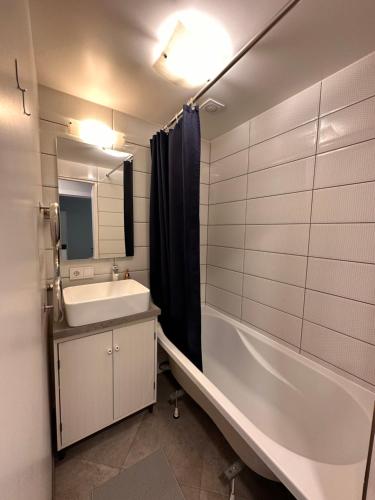 een badkamer met een wastafel, een bad en een spiegel bij Modern city center apartment in Sigulda