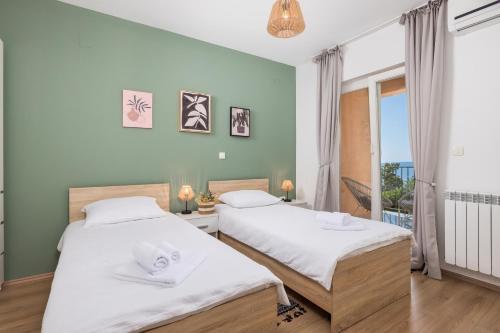 two beds in a room with a window at Villa Oleander Apartman Aria in Poljane
