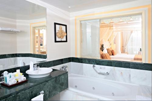 y baño con bañera, lavabo y espejo. en Bahia Principe Luxury Bouganville - Adults Only All Inclusive en La Romana