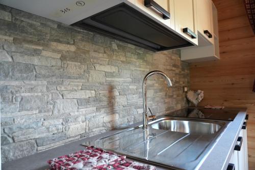een keuken met een wastafel en een stenen muur bij Chalet Navauce in Raveo