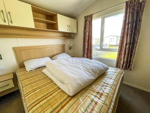 a bedroom with a large bed with a window at Lovely Caravan With Decking At Sand Le Mere Park In Yorkshire Ref 71032tv in Tunstall