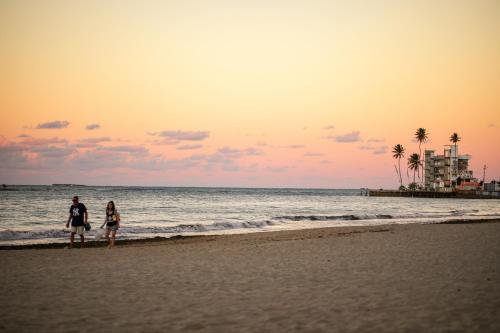 duas pessoas caminhando na praia ao pôr do sol em Tropical Studio at the Beach in Isla Verde em San Juan