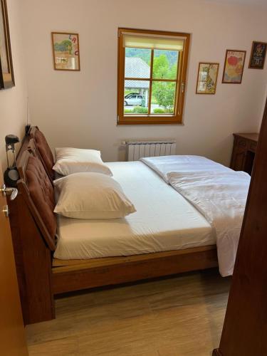 a bed with white sheets and a window in a bedroom at VILA VALANGA in Bovec