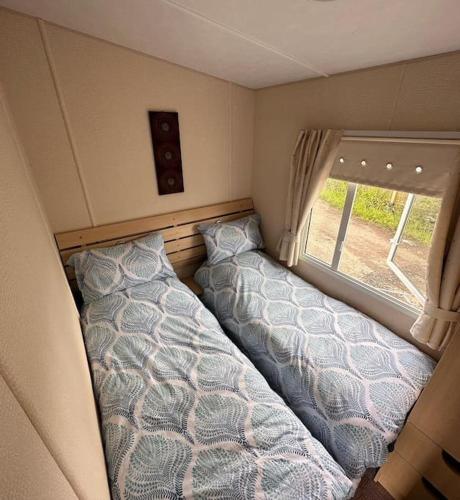 a caravan bedroom with two beds and a window at 4-Bedroom Cosalt Parkhome in Uddingston, Glasgow in Uddingston