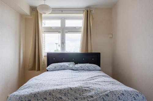 a bedroom with a bed with a blue comforter and a window at Home From Home in London