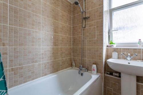 a bathroom with a bath tub and a sink at Home From Home in London