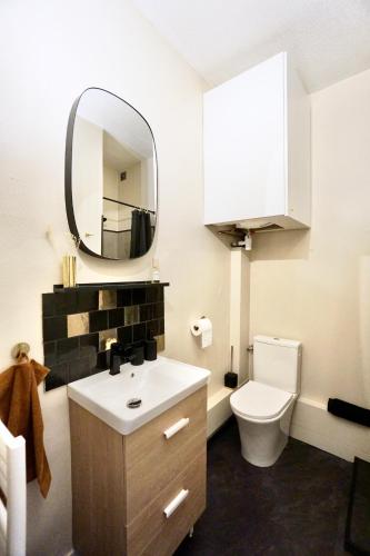 une salle de bain avec des toilettes blanches et un miroir dans l'établissement L'Iconique, à Concarneau