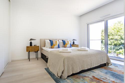 a white bedroom with a bed and a large window at Special Cabanas in Tavira
