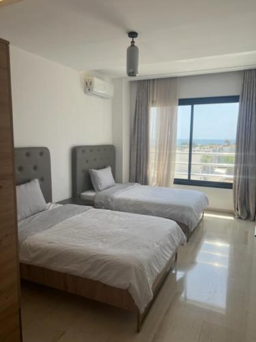 two beds in a room with a window at Residence prestige in Nabeul