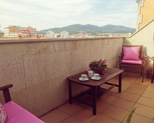 比拉加爾西亞德亞羅薩的住宿－Atico Rias Baixas，阳台上的一张桌子上放着一碗鲜花