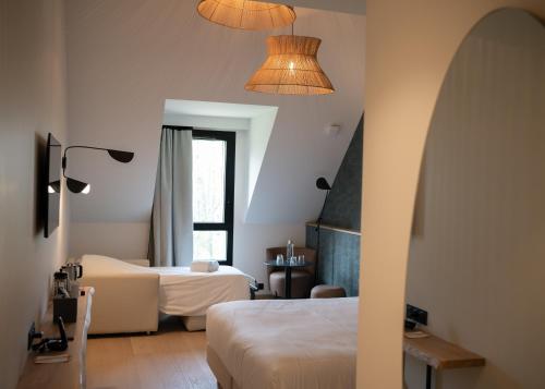 a hotel room with two beds and a window at Auberge de la Caillère in Candé-sur-Beuvron