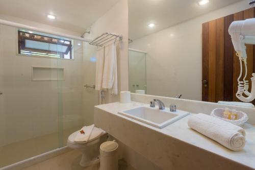uma casa de banho com um lavatório, um WC e um espelho. em Pousada dos Tangarás em Búzios