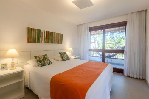 a white bedroom with a bed and a window at Pousada dos Tangarás in Búzios