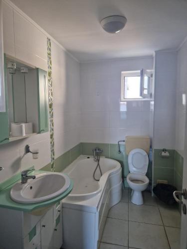 uma casa de banho com uma banheira, um WC e um lavatório. em Maria Residence 1C em Costinesti