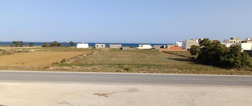 an empty road next to a field and buildings at Dar Lebharr Kélibia in Kelibia