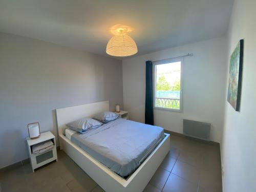 une chambre blanche avec un lit et une fenêtre dans l'établissement Villa 91m2, Piscine, clim, calme, proche plage, à Roquebrune-sur Argens