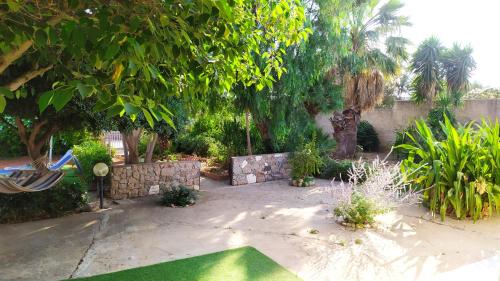 un jardín con una pared de piedra y un césped verde en B&B Il Carlino, en Villaggio Azzurro