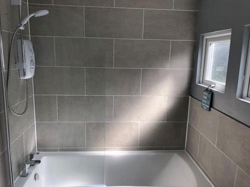 La salle de bains est pourvue d'une baignoire et d'une fenêtre. dans l'établissement The Cosy Cabin - Bideford Bay Holiday Park, à Bucks Mills