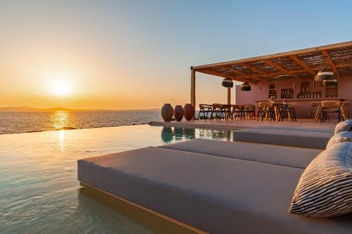 a pool with a view of the ocean at sunset at Akre Hotel - Designed for Adults in Naxos Chora