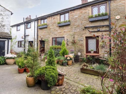 a garden in front of a brick building with potted plants at 17th Century 2-bed/bath period cottage in Barrowford