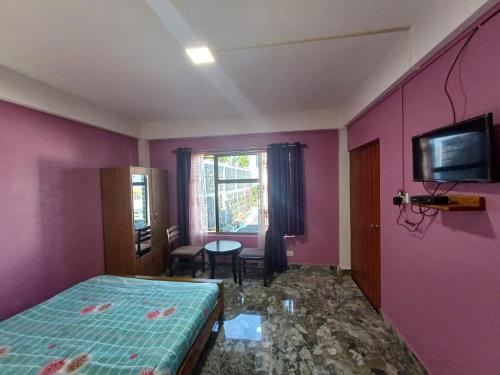 1 dormitorio con 1 cama y TV en la pared en Odyssey Stays Nongrim, Cherrapunji, en Cherrapunji