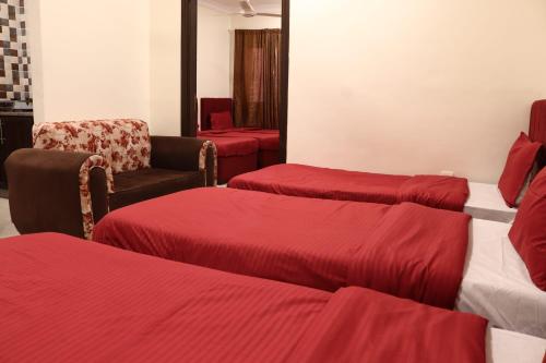 ein Hotelzimmer mit 3 Betten und einem Stuhl in der Unterkunft Future 2 Hotel Apartments in Aqaba