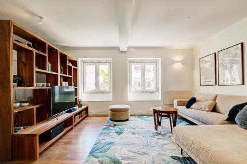 uma sala de estar com um sofá e uma televisão em Comfortable Town House in Quiet Area by LovelyStay em Lisboa