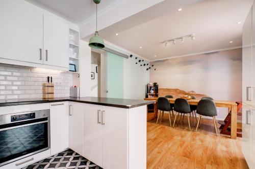 a kitchen with white cabinets and a table with chairs at Comfortable Town House in Quiet Area by LovelyStay in Lisbon