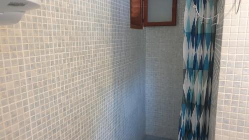 eine weiß geflieste Dusche mit einem blauen Duschvorhang in der Unterkunft TAKOMA in Čunski