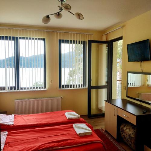 a bedroom with a bed and a television and windows at Къща за гости СИАНА in Dospat