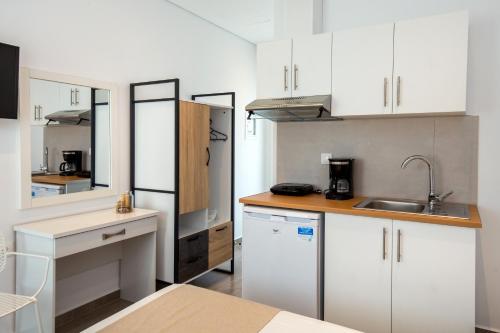 uma pequena cozinha com armários brancos e um lavatório em Studio central Potos em Potos