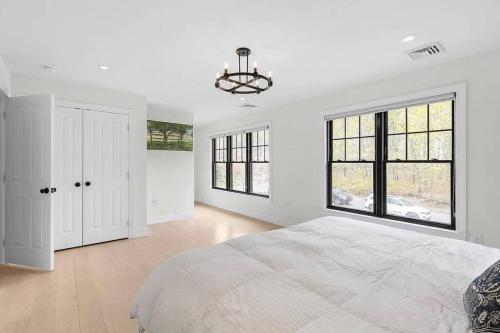 una camera bianca con un grande letto e finestre di Stylist East Hampton Home a East Hampton