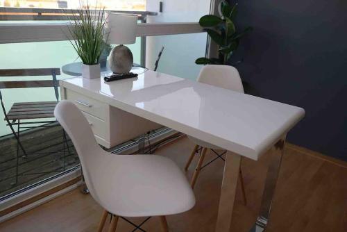 einen weißen Schreibtisch mit zwei weißen Stühlen und einer Lampe in der Unterkunft Luftiges Apartment im Herzen von Dresden in Dresden