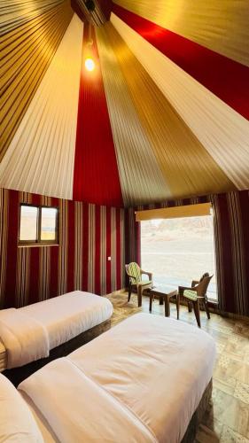 a bedroom with two beds and a red and yellow ceiling at Lulua luxury camp in Wadi Rum