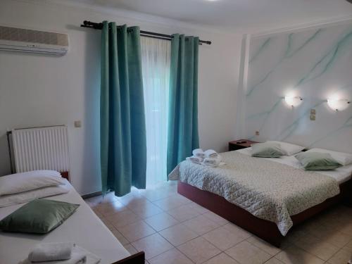 a bedroom with two beds and green curtains at Anassa Deluxe Apartments & Studios in Skala Potamias