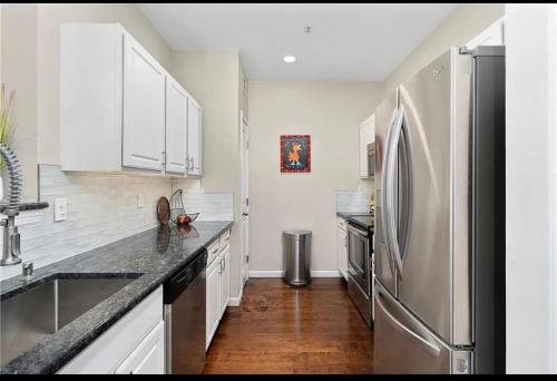 una cocina con nevera de acero inoxidable y armarios blancos en Downtown Shared Apartment, en Providence