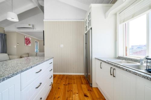 科爾切斯特的住宿－The Slipway，厨房配有白色橱柜、水槽和窗户。