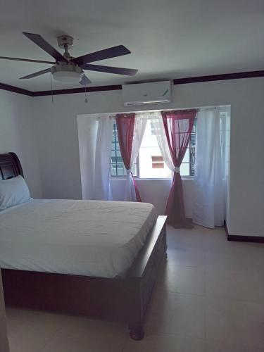 a bedroom with a bed and a ceiling fan at Sea Breeze Penthouse Apartment in Kingston