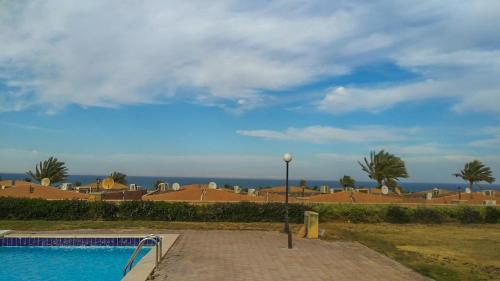 a swimming pool with a light pole next to a house at Rania Chalet -Stella Di Mare Sea view- Families in Ain Sokhna