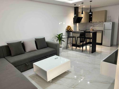 a living room with a couch and a table and a kitchen at Appartement cosy à l'Aouina in Tunis