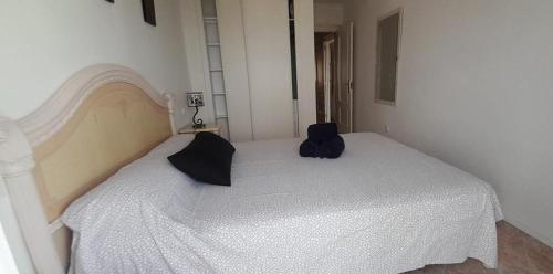 a bedroom with a white bed with a black backpack on it at CarihuelaCity in Torremolinos